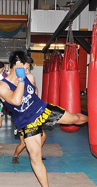 Boxeur, coup de pied au sac de frappe, à Bangkok